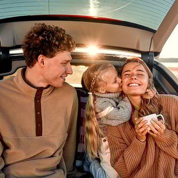 happy young couple with daughter sitting in the truck of their SUV