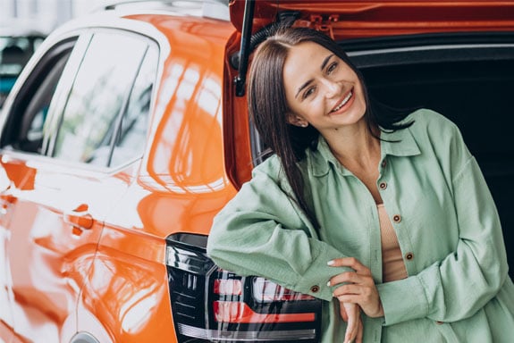 A-car-loan-pre-approval-from-Peach-State-Federal-Credit-Union-helped-this-woman-in-a-green-suit-smiling-get-her-new-orange-car.