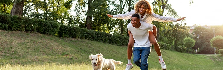 African american young couple in love runs with dog in the park in the summer and smiles