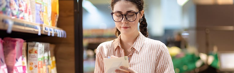 Caucasian woman wearing eyeglasses holds product list in supermarket and write in it.-1