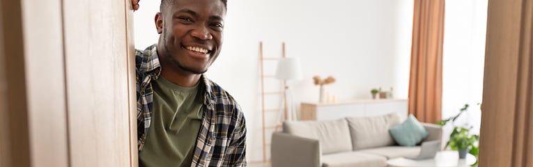 Cheerful African American Guy Opening Door of His House Indoors