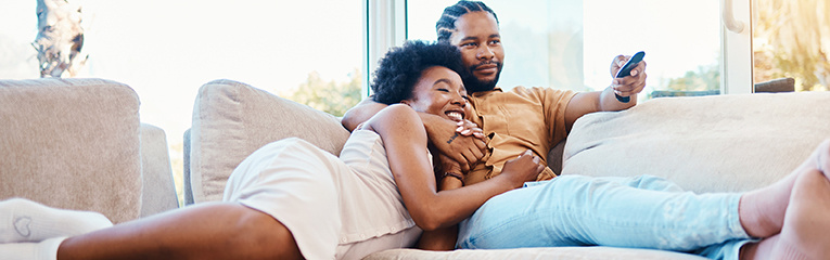 Couple, watching tv and relax on home sofa together