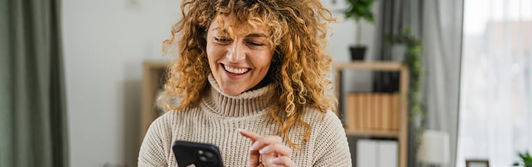 Excited adult woman use mobile phone for fun at home stock photo