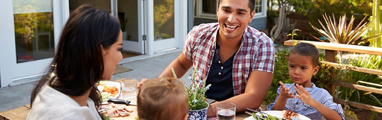 Family At Home Eating Outdoor Meal In Garden Together