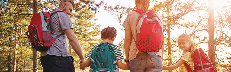 Family with backpacks on the nature near the sea. Concept of the family hiking and joint resting.