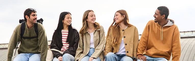 Group of diverse students relaxing and chatting on a brick wall
