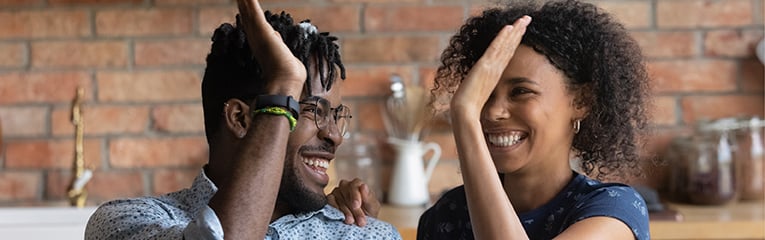 Happy excited Black mixed race couple celebrating success at laptop