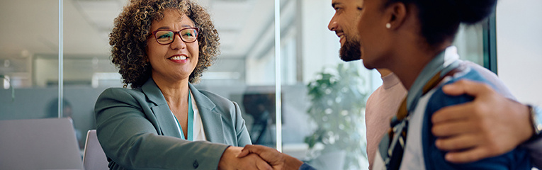 Happy financial advisor greeting young couple in the office.