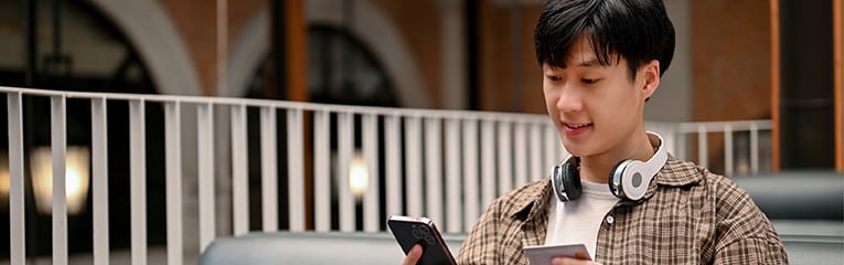 Happy man holding a smartphone and a credit card, using mobile banking
