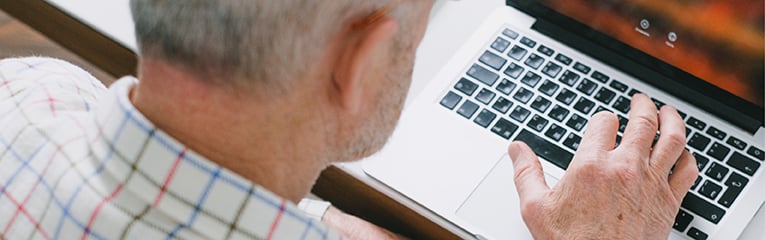 Older caucasian man at laptop typing one handed