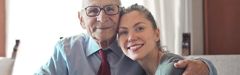 Older caucasian man with armed wrapped around teenage granddaughter smiling
