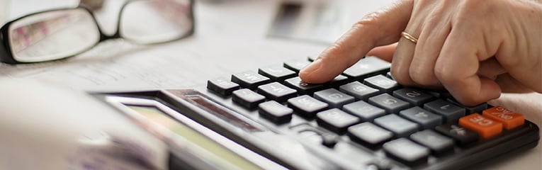 Older hands counting finances on a home calculator