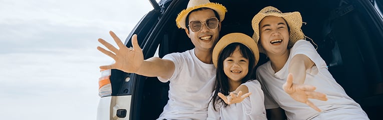 Parents and children daughter enjoying road trip sitting on family back car waving to camera