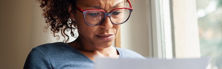 Sad black woman near window reading bad news letter