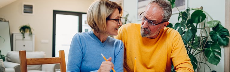 Senior couple sitting at table and looking into blueprints of their new home