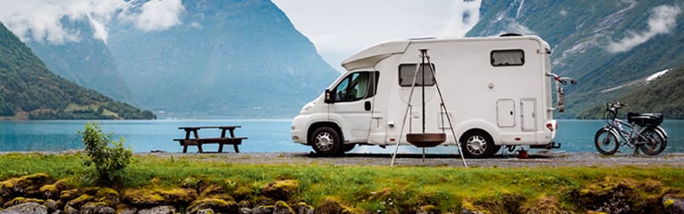 Small RV parked surrounded by water and mountains