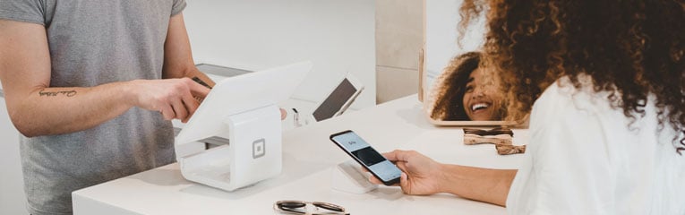 Woman-using-her-mobile-wallet-on-her-cell-phone-to-buy-her-sunglasses-at-a-boutique.