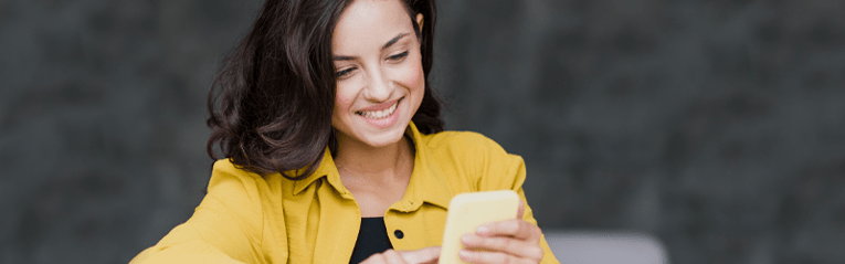 woman in yellow looking at cell