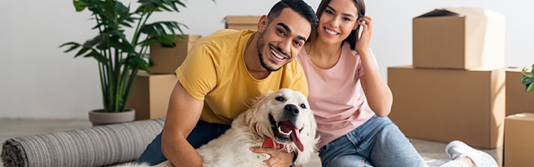 young diverse couple with their dog posing on floor of new home on moving day-1