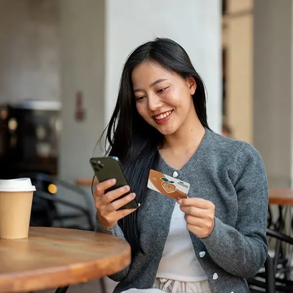 Woman looks at phone while shoppoing with PSFCU visa debit card