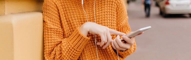 Woman-exploring-consolidation-loans-on-her-cellphone-while-wearing-orange-sweater.