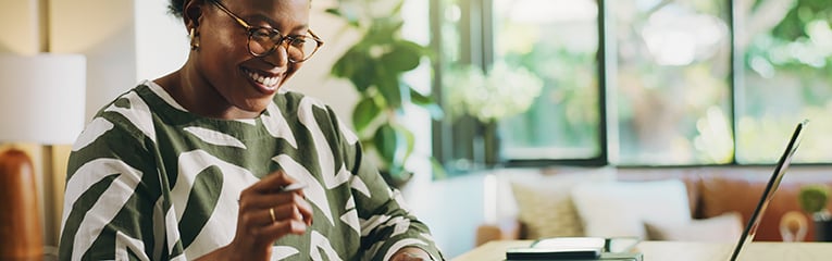 Happy, black woman and finance with laptop for payroll, tax return or budget planning at home.