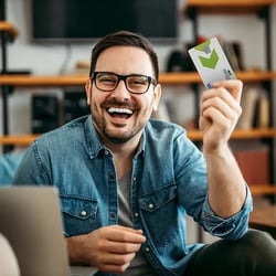 Middle aged man smiles while holding PSFCU Visa Credit Card