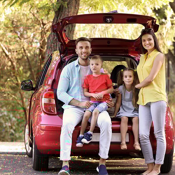 Family poses on parked car