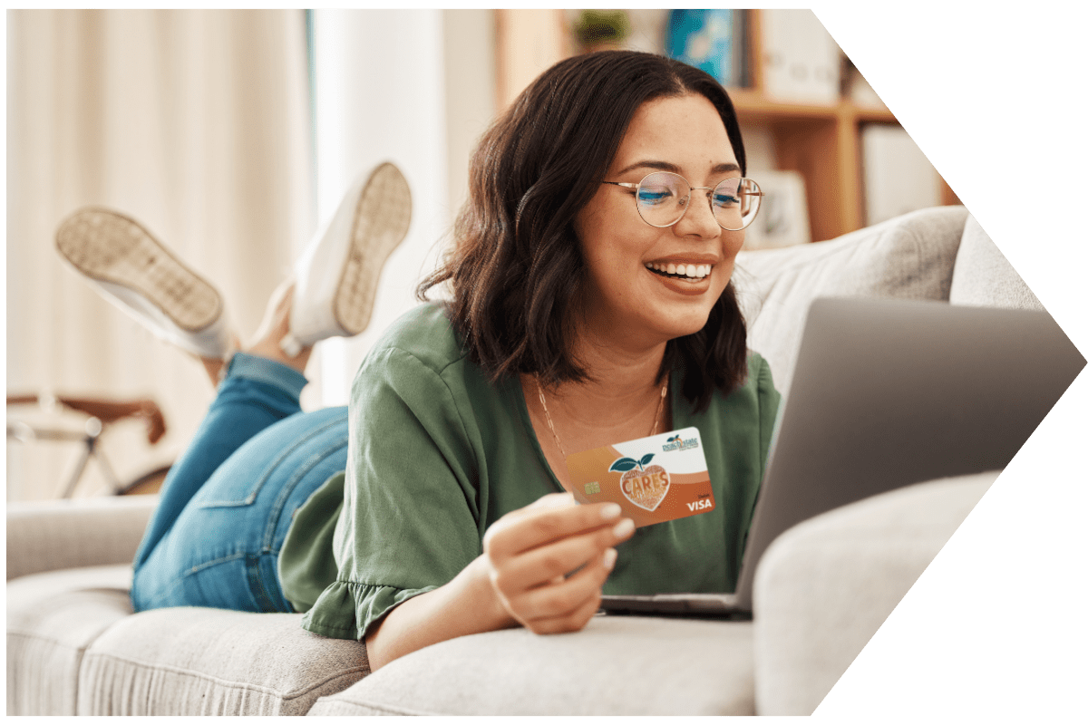 Teen lays on couch shopping with PSFCU visa debit card