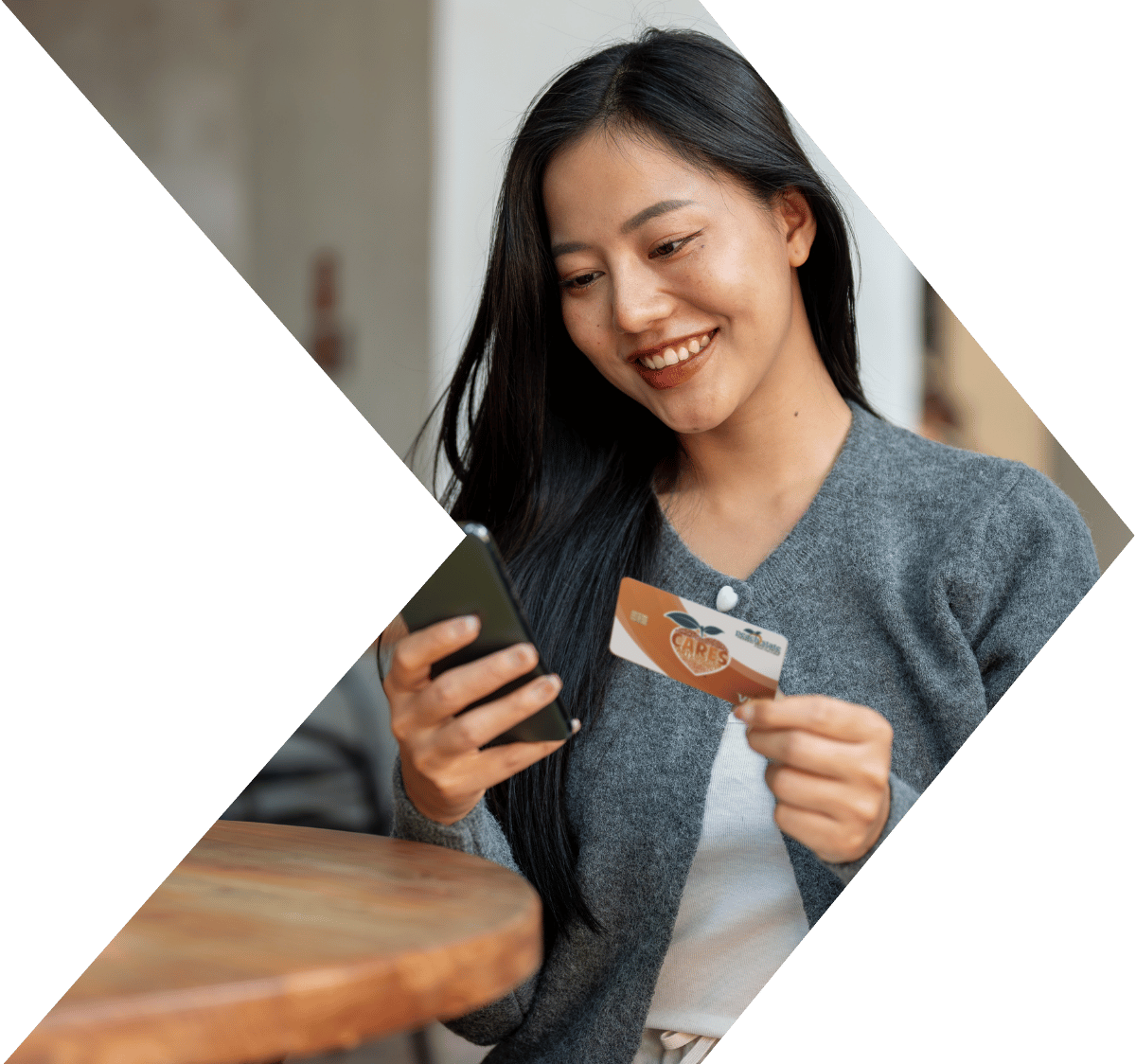Woman looks at phone while shoppoing with PSFCU visa debit card