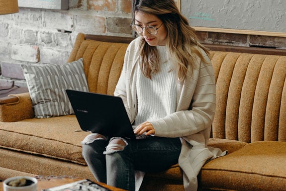 Woman-discovering-how-to-get-out-of-debt-by-using-Peach-States-roadmap-on-her-laptop-while-sitting-on-a-tan-couch.