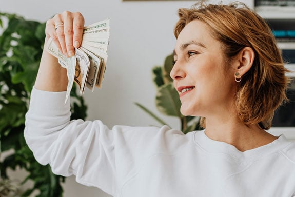 Woman-smiling-holding-her-52-week-money-challenge-cash-savings-she-accumulated-over-the-year.