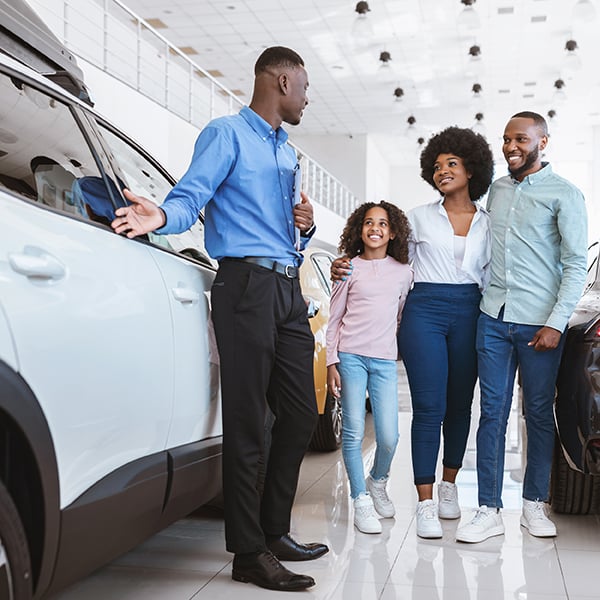 Family speaks with salesman's at auto dealer