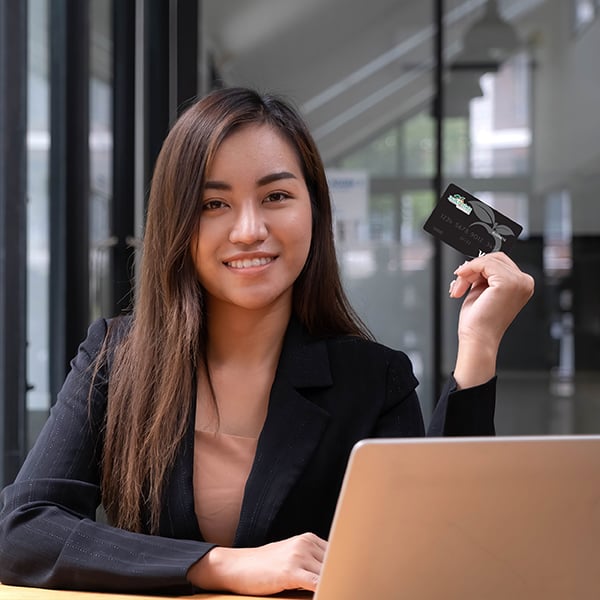 Woman smiles while holding her Peach State Business Visa card