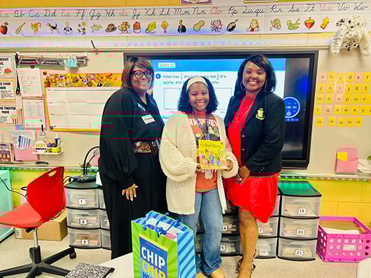 peach state rep with teachers holding berenstain bears book in classroom