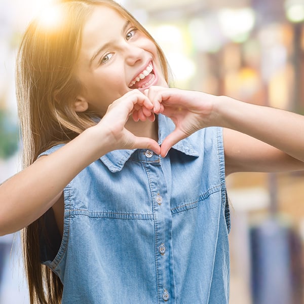 Young girl makes a heart with her hands