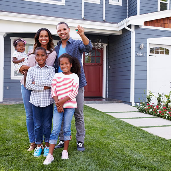 Family poses outside of new home