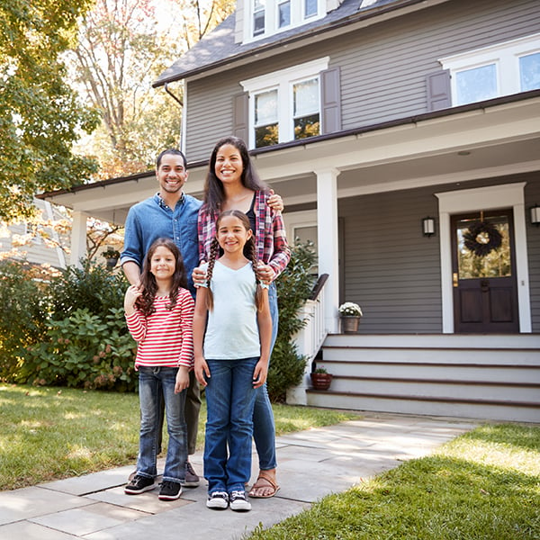 Family stands in front of their newly insured home