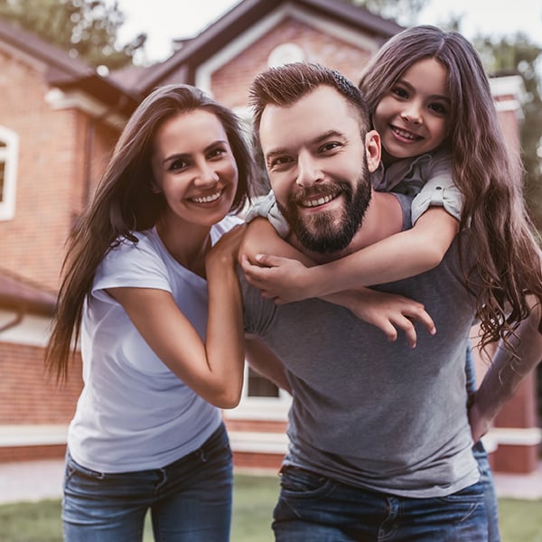 Family smiles in front of their home