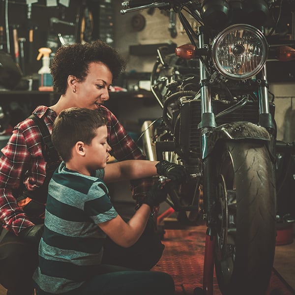 Mother and son work on motorcycle together