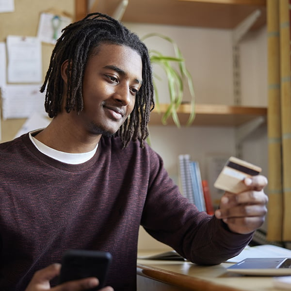 A young man looks at his Peach State Debit Card after adding Overdraft Protection.