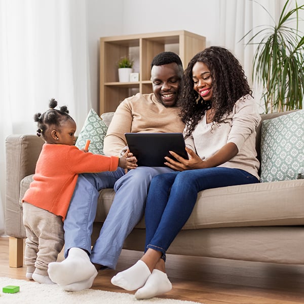 Young family check iPad together on couch