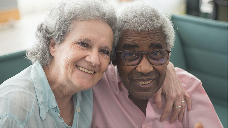 Bi-racial older couple holding each other and smiling