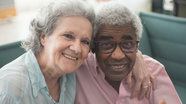 Bi-racial older couple holding each other and smiling