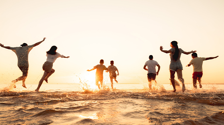 Big group of young diverse friends or big family are having fun and run at sunset beach.