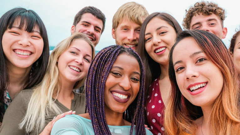 A diverse group of college students smiling into the camera.