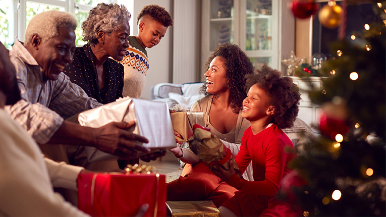 African American multigeneration family exchanging gifts, smiling and laughing during the holidays