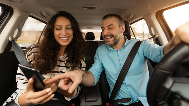 Couple-refinanced-their-car-loan-and-are-driving-away-happy-looking-at-the-savings.