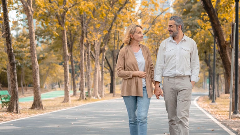 Couple-walking-on-a-tree-lined-path-discussing-which-savings-account-whill-earn-them-the-most-money.