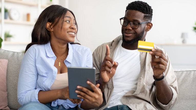 Credit cards for bad credit helped this couple checking their credit score on a tablet improve their score.